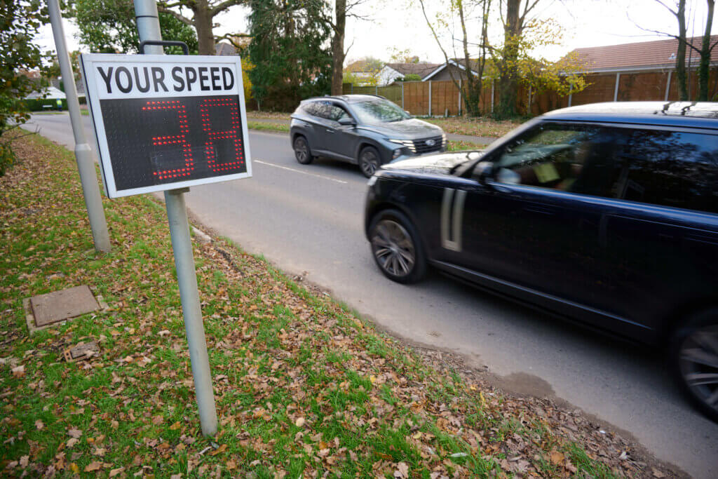 cars on road passing a sign showing speed travelling