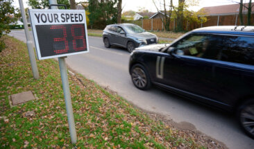 cars on road passing a sign showing speed travelling