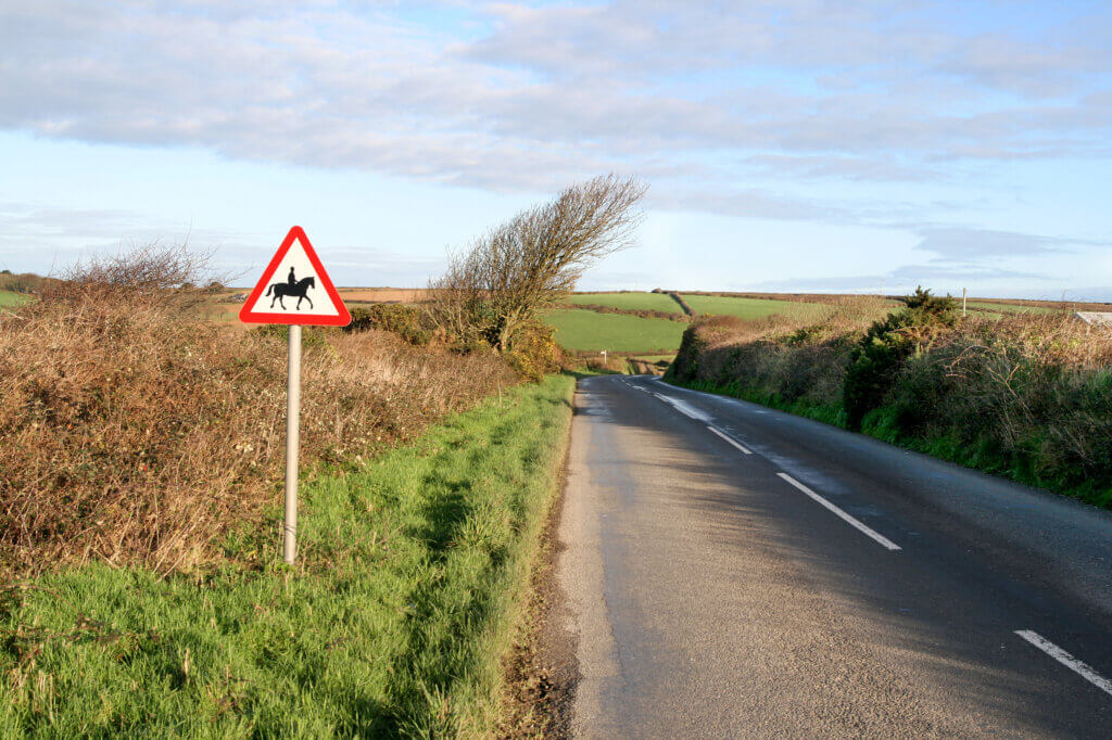 Country road with horse riders signpost