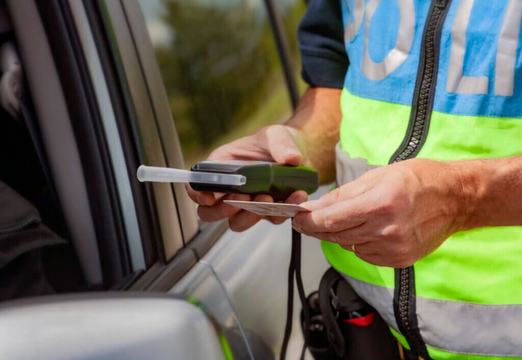 Policeman holding device for checking alcohol intoxication while standing near the stopped car