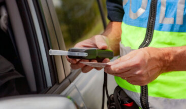Policeman holding device for checking alcohol intoxication while standing near the stopped car