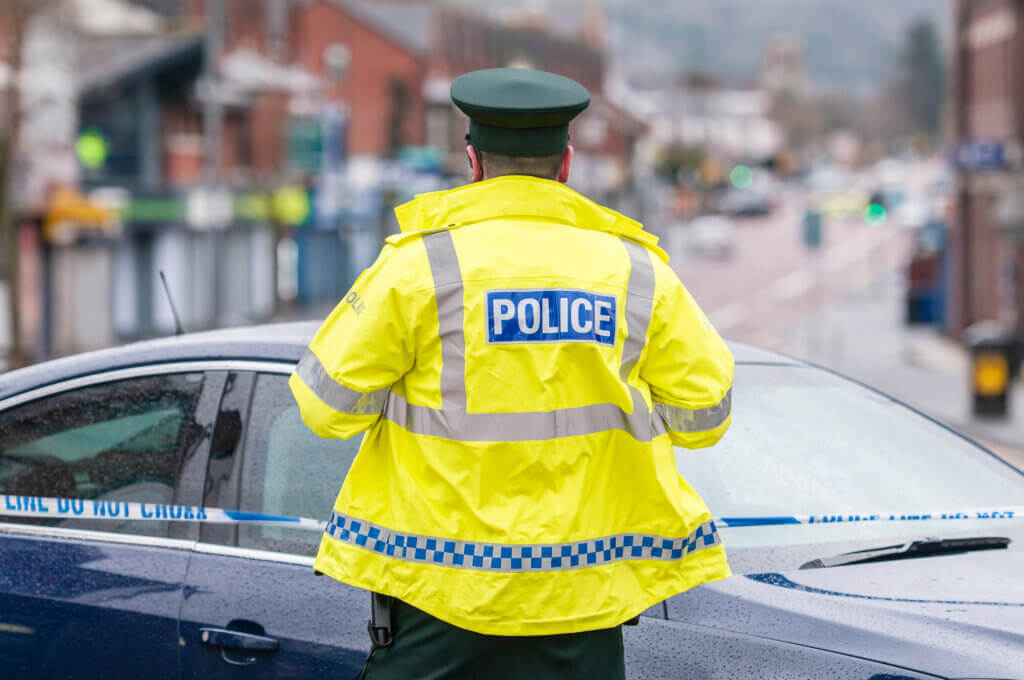 A Psni Police Officer Stands At A Police Cordon