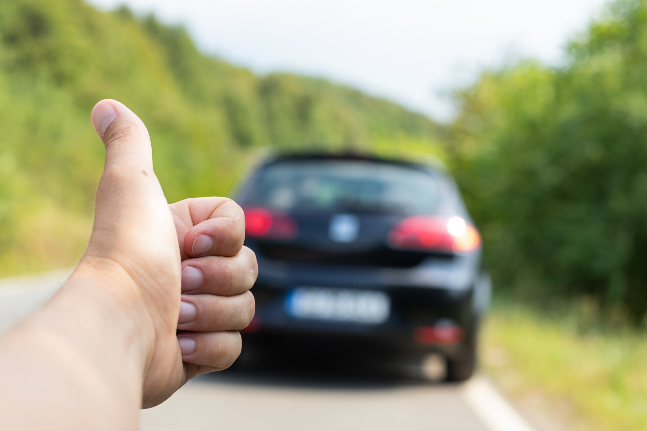 Thumbs up behind car